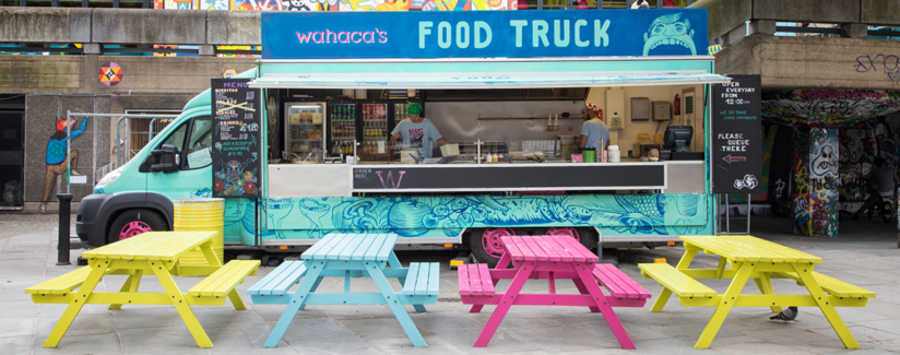 Blue food truck with colorful benches in front